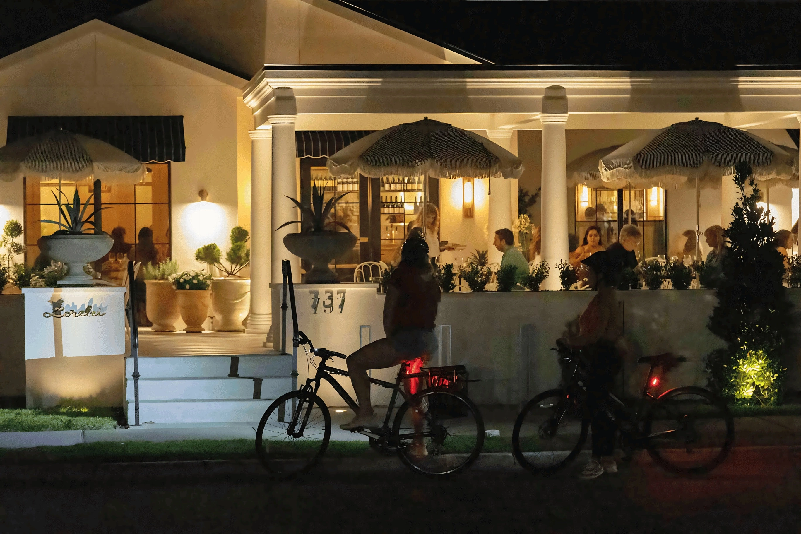 Cyclists passing a warmly lit restaurant patio on an Orlando night tour
